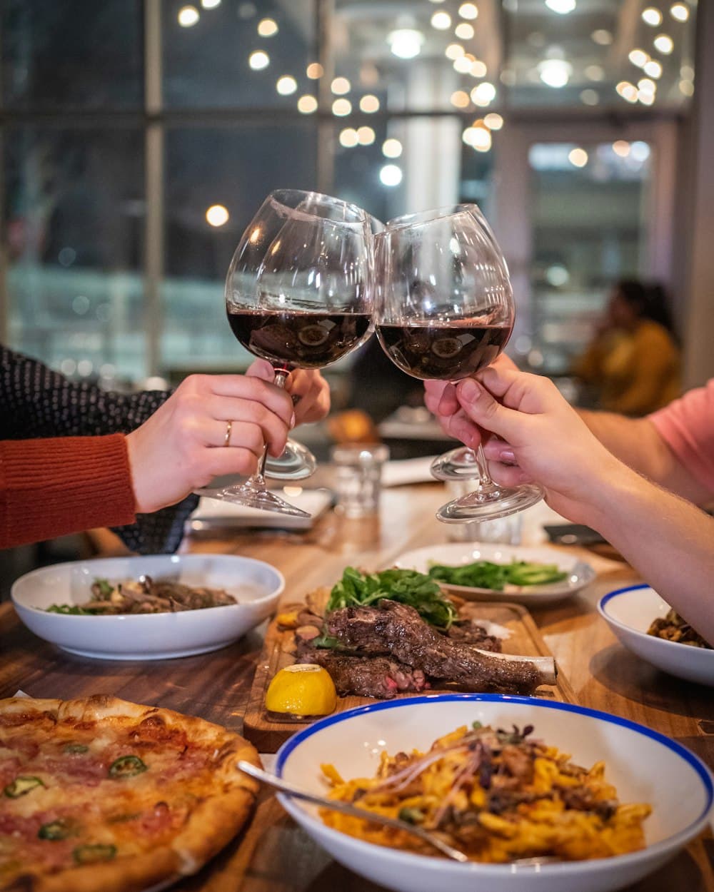 Friends clinking glasses of red wine over dinner