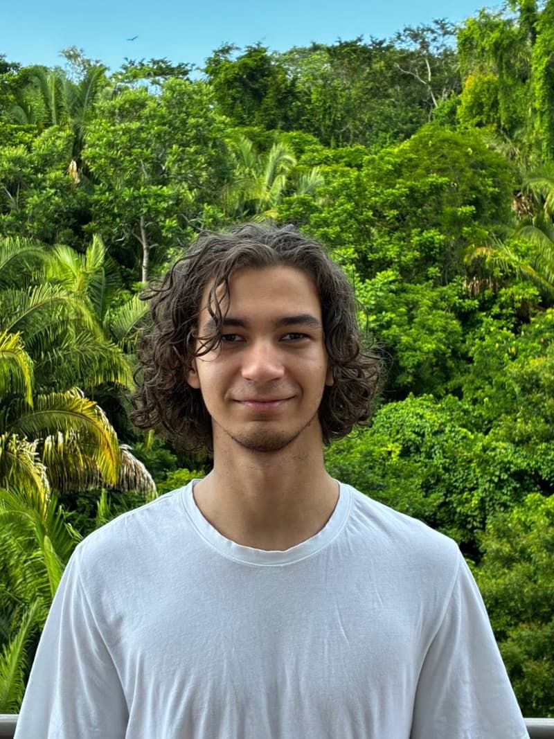 Edward, founder of Elegix, smiling in a white T-shirt in front of tropical greenery